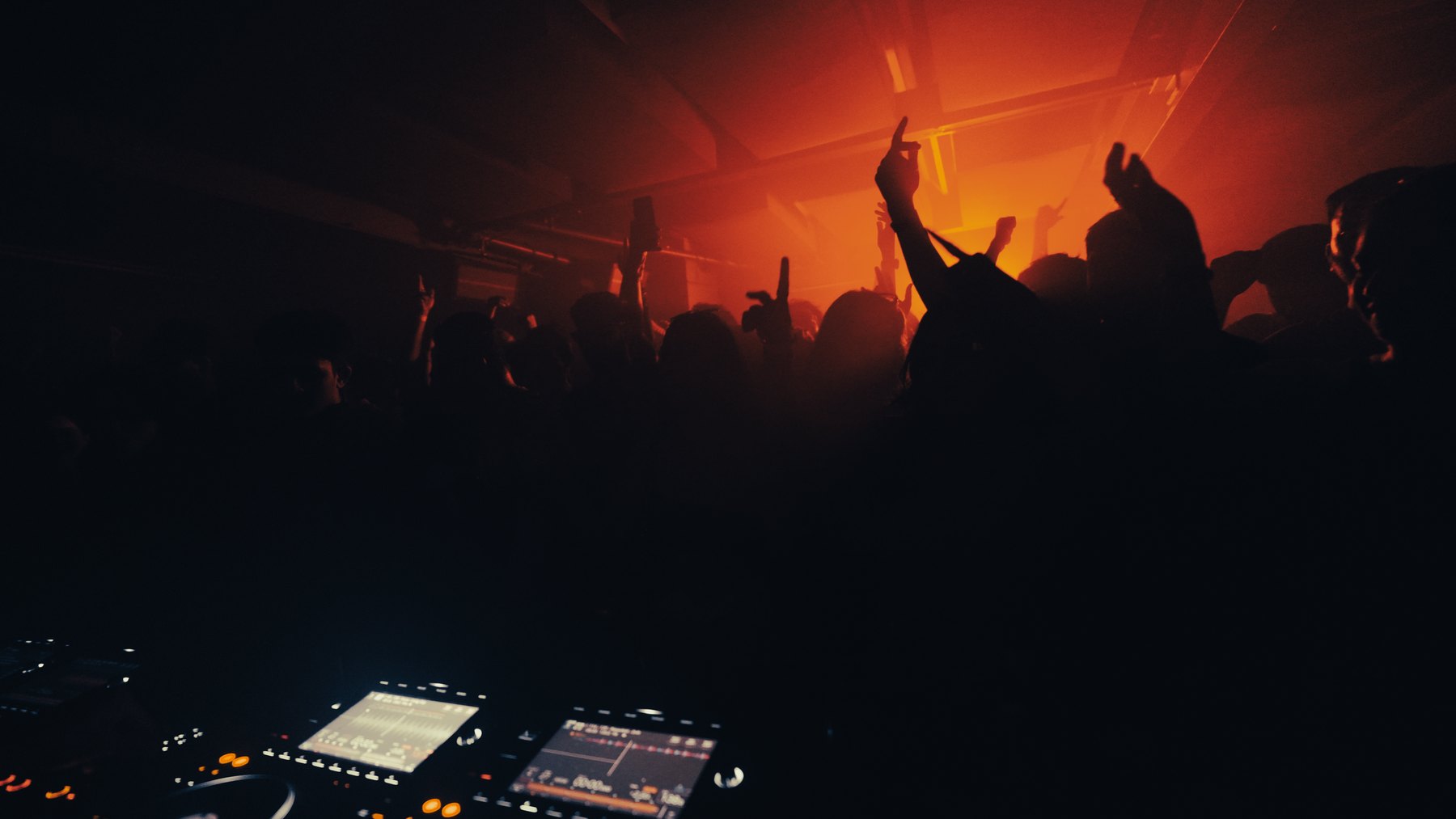 Dancefloor silhouettes and raised hands photographed by TripTuner
